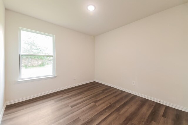spare room with baseboards and dark wood finished floors