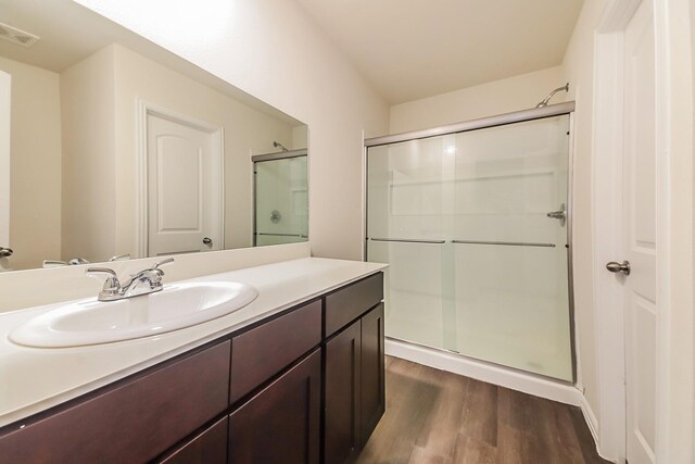 bathroom with visible vents, a stall shower, wood finished floors, and vanity
