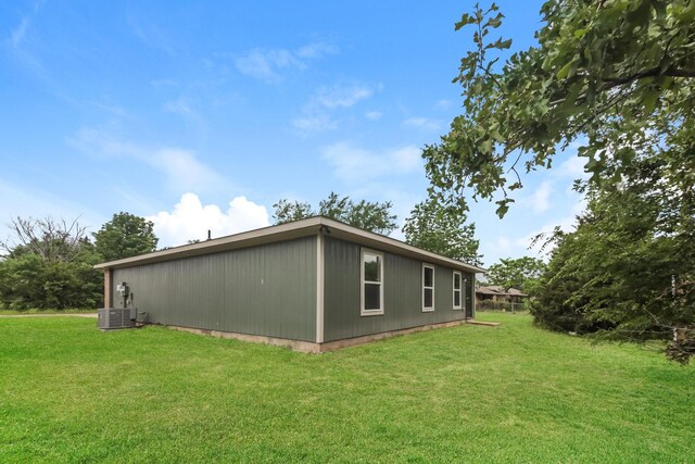 view of side of home with a lawn and central air condition unit