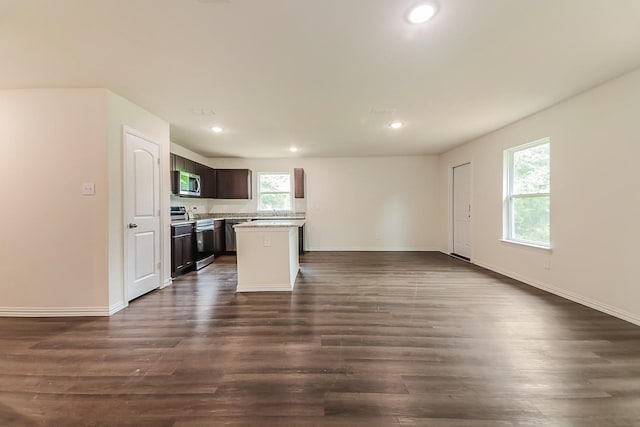 kitchen with appliances with stainless steel finishes, dark brown cabinets, light countertops, open floor plan, and recessed lighting