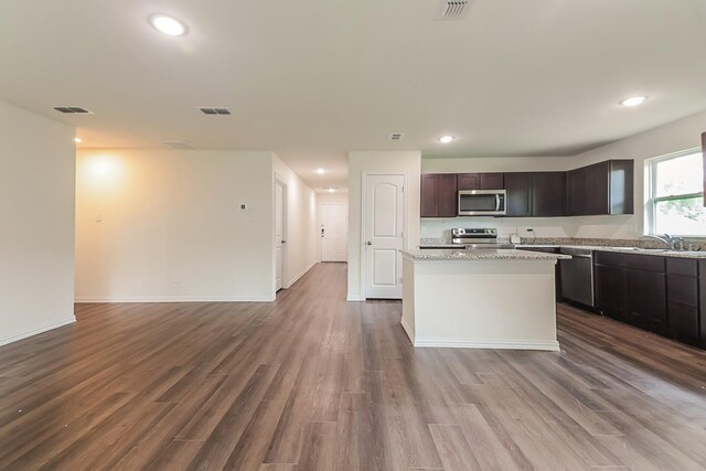 kitchen with a sink, appliances with stainless steel finishes, a kitchen island, and recessed lighting