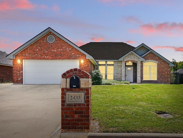 view of front of property featuring a lawn, a garage, driveway, and brick siding
