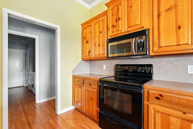 kitchen with ornamental molding, decorative backsplash, stainless steel microwave, black electric range, and independent washer and dryer