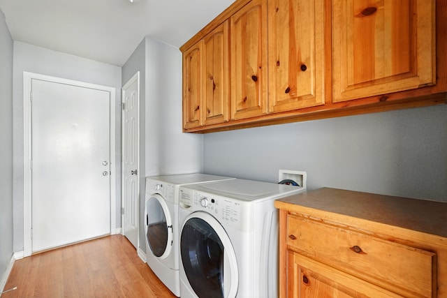 washroom featuring baseboards, light wood-style flooring, cabinet space, and independent washer and dryer