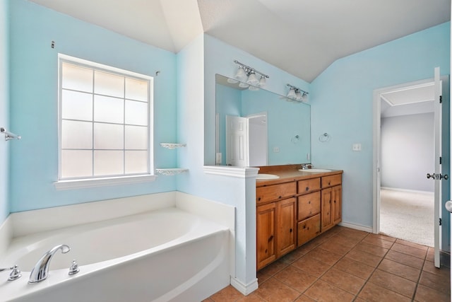 bathroom featuring a sink, double vanity, tile patterned floors, vaulted ceiling, and a bath