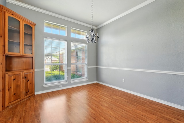 unfurnished room with crown molding, baseboards, wood finished floors, and a chandelier