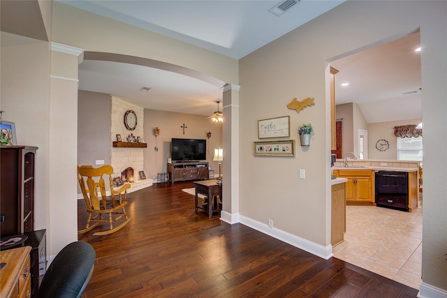 corridor featuring visible vents, arched walkways, light wood-type flooring, a sink, and baseboards