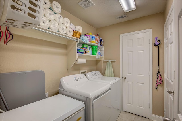 laundry room with visible vents, laundry area, light tile patterned flooring, and washing machine and clothes dryer