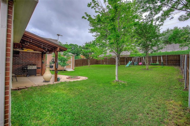 view of yard featuring a fenced backyard, a fire pit, a patio area, and a playground
