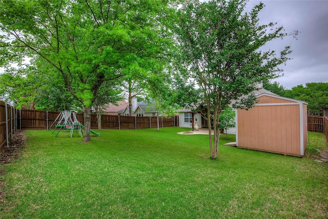 view of yard with an outdoor structure, a fenced backyard, a playground, and a shed