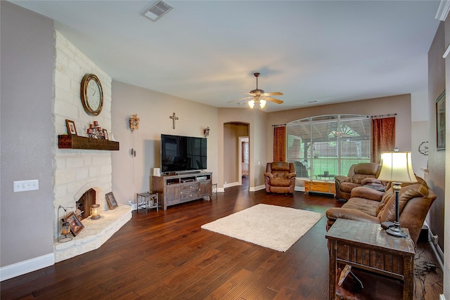 living room featuring ceiling fan, a fireplace, arched walkways, wood finished floors, and visible vents