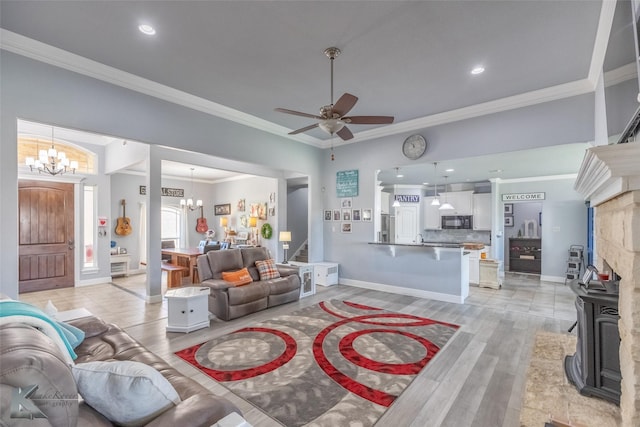 living area featuring ornamental molding, stairs, light wood-style floors, baseboards, and ceiling fan with notable chandelier