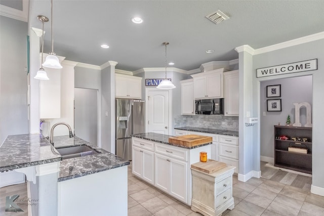kitchen with a sink, dark stone countertops, a peninsula, backsplash, and black appliances