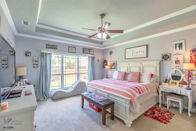 bedroom featuring visible vents, ornamental molding, a raised ceiling, and light carpet
