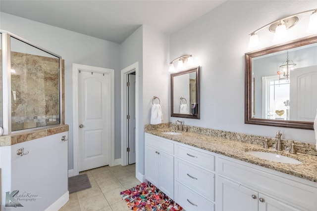 bathroom with double vanity, tiled shower, a sink, and tile patterned flooring
