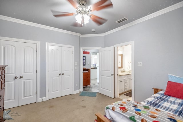 bedroom with light colored carpet, crown molding, visible vents, connected bathroom, and multiple closets