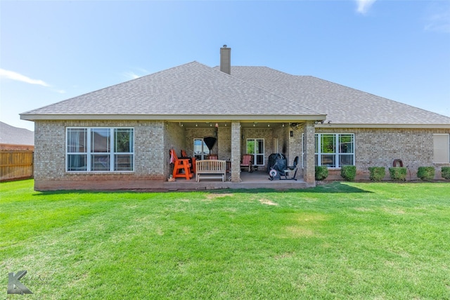back of property featuring roof with shingles, a lawn, and brick siding