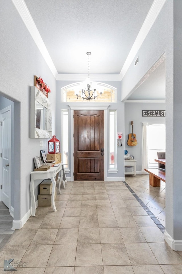 entrance foyer with light tile patterned flooring, a notable chandelier, baseboards, visible vents, and ornamental molding