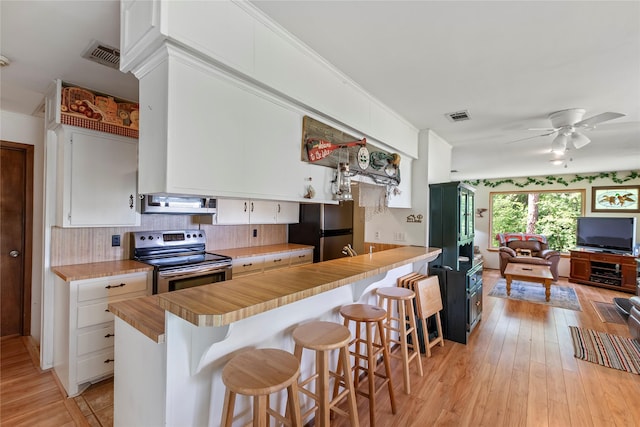 kitchen featuring visible vents, open floor plan, ceiling fan, a kitchen bar, and appliances with stainless steel finishes