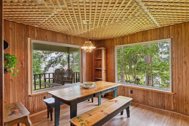 dining space featuring wood walls and a notable chandelier