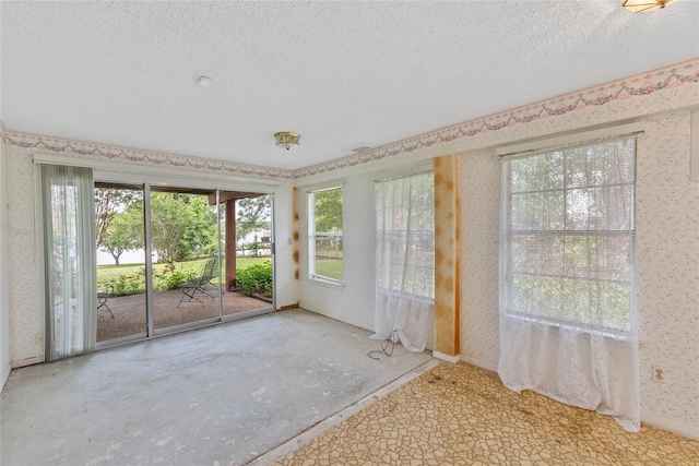 unfurnished sunroom with a textured ceiling and wallpapered walls