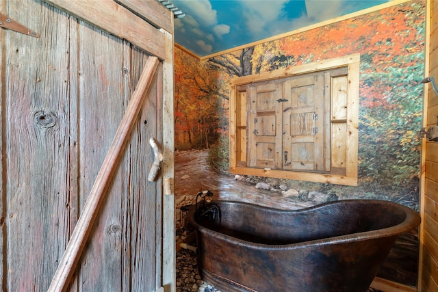 bathroom with a freestanding tub and wallpapered walls