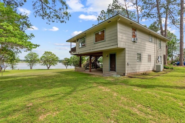 back of property with cooling unit, a patio, stairs, a water view, and a yard