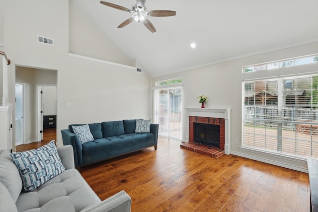 living room with ceiling fan, visible vents, wood finished floors, and a fireplace