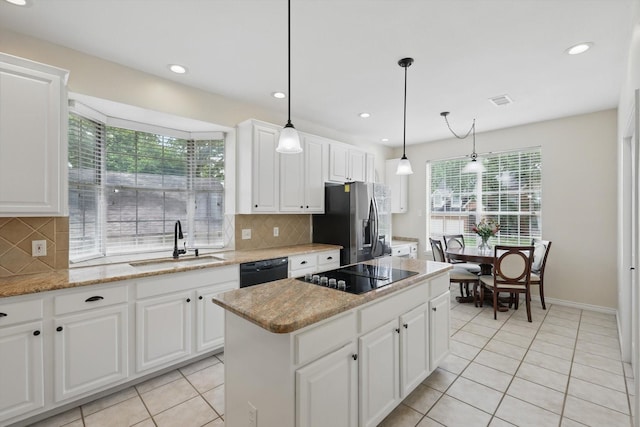 kitchen featuring a sink, light tile patterned floors, a kitchen island, and black appliances