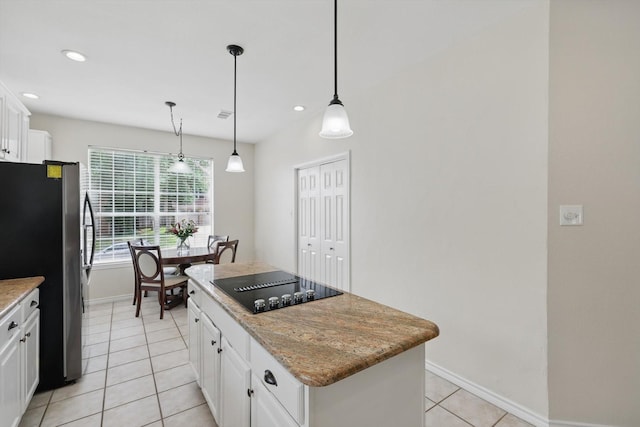 kitchen with black electric stovetop, a center island, freestanding refrigerator, baseboards, and light tile patterned floors