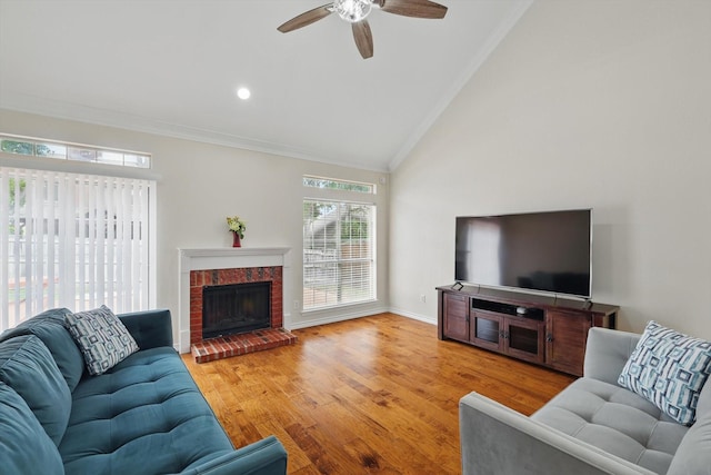 living area with a ceiling fan, a fireplace, vaulted ceiling, wood finished floors, and ornamental molding