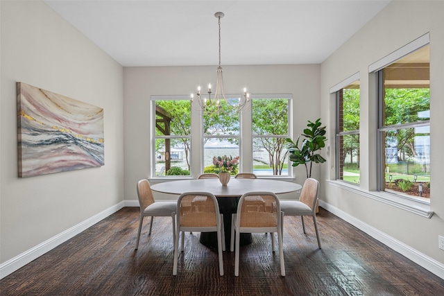 dining space featuring dark wood-style flooring, baseboards, and a notable chandelier