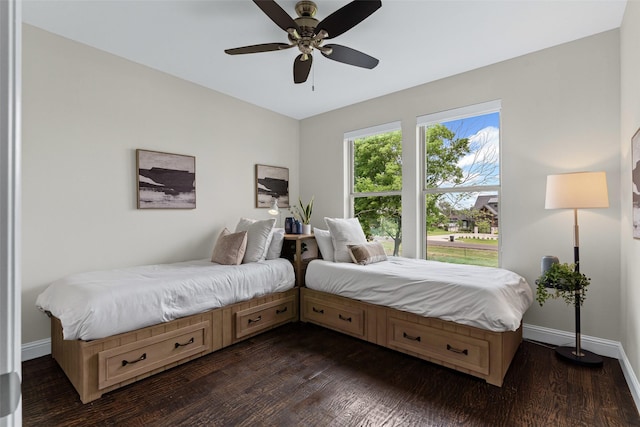 bedroom with a ceiling fan, baseboards, and dark wood-style floors