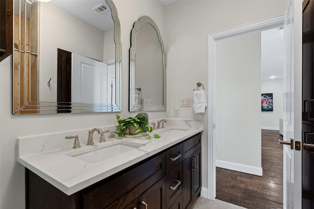 bathroom featuring double vanity, visible vents, a sink, and wood finished floors