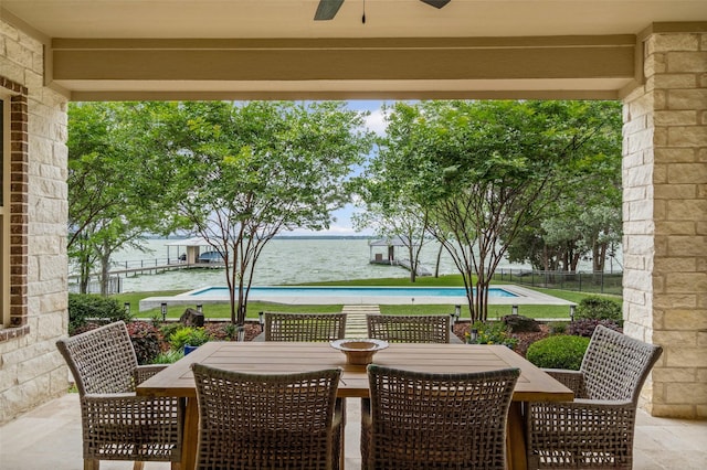 view of patio with a water view, a ceiling fan, a fenced in pool, and outdoor dining area