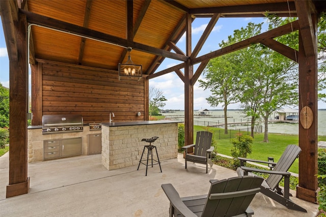 view of patio / terrace featuring a water view, outdoor wet bar, grilling area, and area for grilling