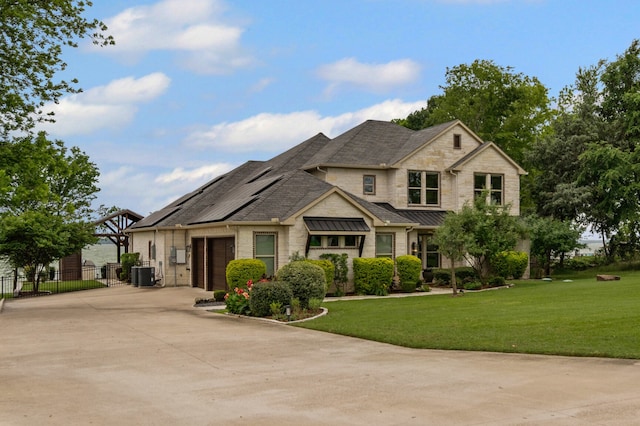 view of front of property with a standing seam roof, driveway, central AC unit, a garage, and a front lawn