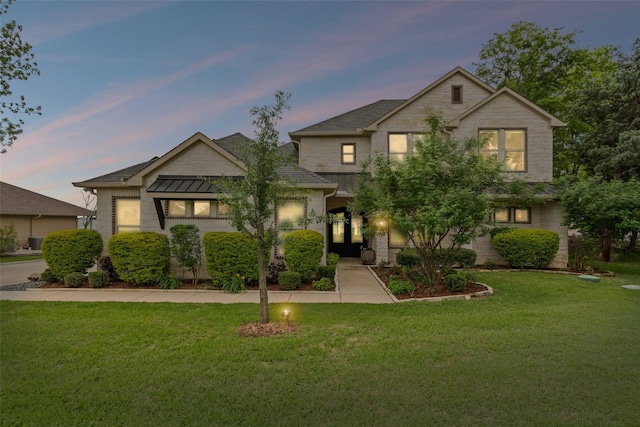 view of front of home featuring a yard, a shingled roof, and stone siding