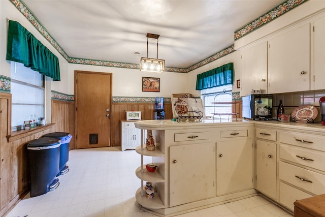 kitchen with open shelves, wainscoting, a peninsula, tile countertops, and hanging light fixtures
