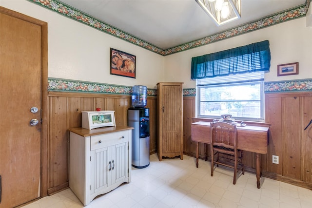 home office featuring wood walls, wainscoting, water heater, and light floors