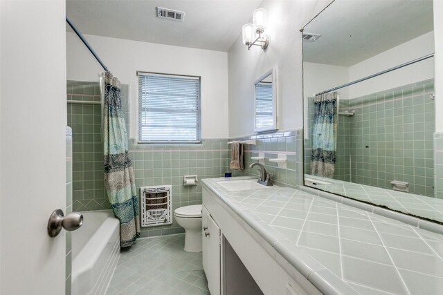 bathroom featuring visible vents, heating unit, toilet, tile walls, and tile patterned floors