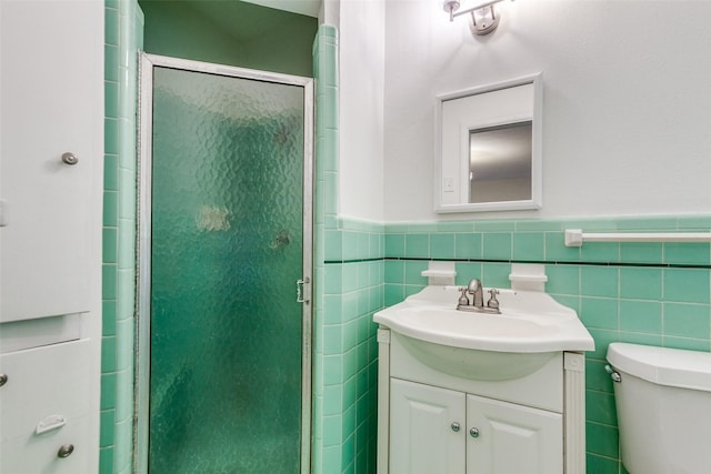bathroom featuring toilet, tile walls, a shower stall, and vanity