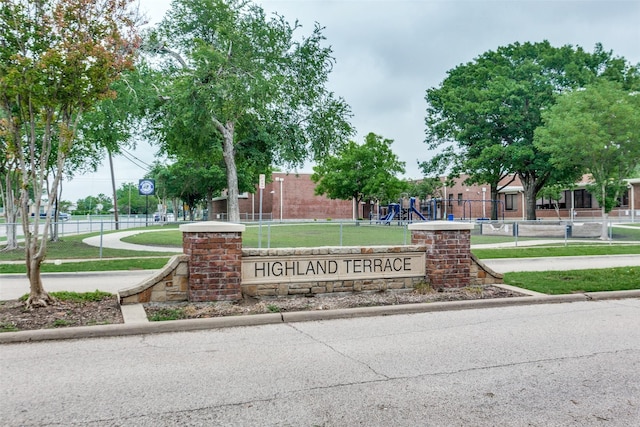 community / neighborhood sign featuring fence and a yard