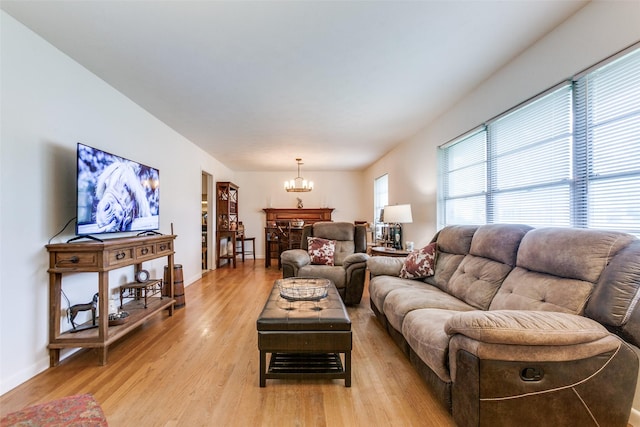 living area featuring baseboards, a notable chandelier, and light wood-style flooring