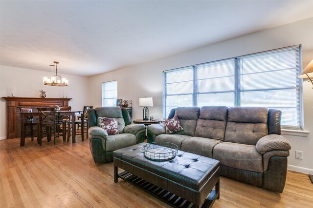 living room featuring an inviting chandelier, baseboards, and light wood finished floors