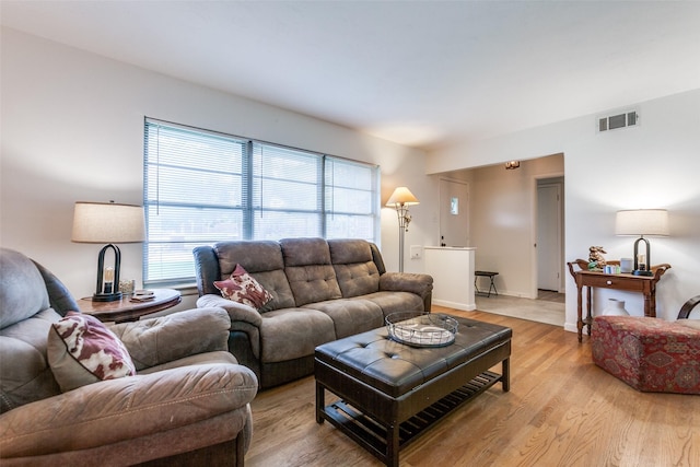 living room with visible vents, light wood-style flooring, and baseboards