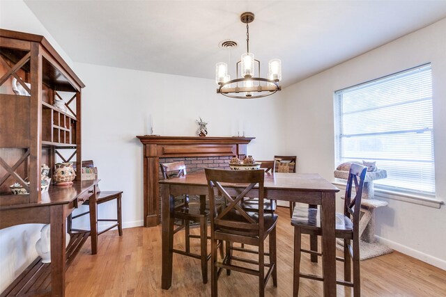 dining space featuring baseboards, visible vents, light wood finished floors, and a chandelier