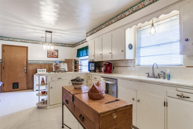 kitchen with stainless steel dishwasher, white cabinets, and a wealth of natural light