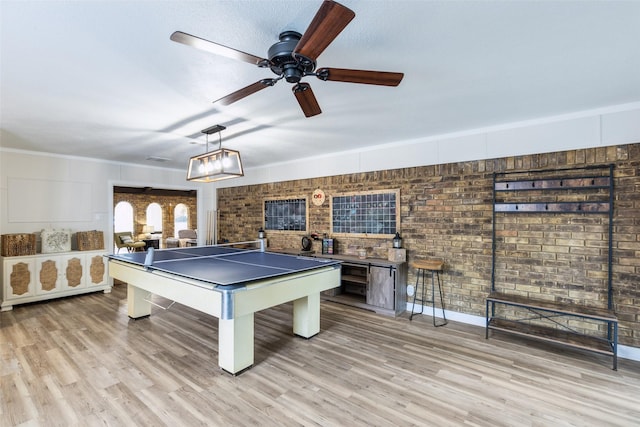 recreation room featuring light wood-type flooring, billiards, a ceiling fan, and brick wall
