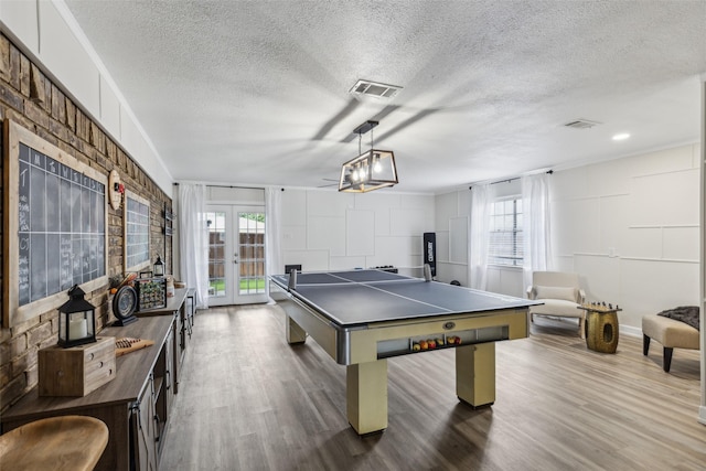 rec room with wood finished floors, french doors, a textured ceiling, and visible vents
